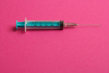 Medical syringe on a pink background. A syringe for injection. The concept of health and beauty