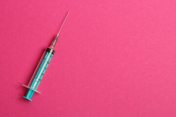 Medical syringe on a pink background. A syringe for injection. The concept of health and beauty