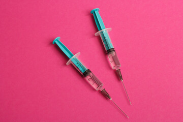 Fototapeta premium Medical syringe on a pink background. A syringe for injection. The concept of health and beauty