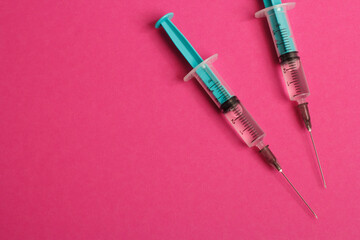 Medical syringe on a pink background. A syringe for injection. The concept of health and beauty