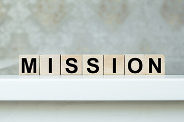 Mission text on wooden cubes that stand on a white table in isolation