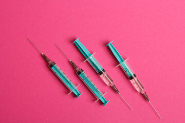 Fototapeta premium Medical syringe on a pink background. A syringe for injection. The concept of health and beauty