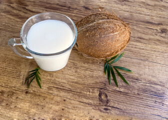 Glass cup with coconut milk and coconut on wooden background 