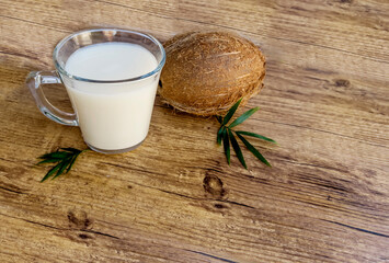Glass cup with coconut milk and coconut on wooden background 
