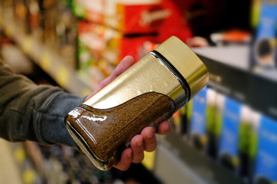 male hand holds can of coffee on blurred background, row of shelves with groceries in supermarket, concept of marketing, prices for consumer goods, consumer basket, rising prices for essential goods