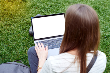 A mockup of a laptop in a girl's lap on the street. A woman works with a laptop in the fresh air in...