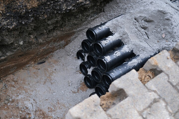 lot of new black pipes for protecting electrical wires in trench on street, concept of repairing...