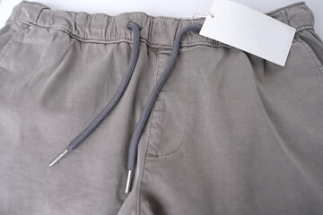 close-up of texture of gray cotton trousers, pants with welt pockets, ankle cuffs, drawstring at...