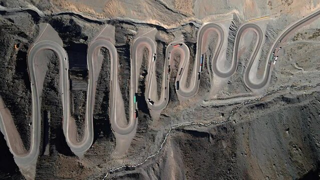 Aerial overhead truck right view of the Cuesta Caracoles road, border between Chile and Argentina, cars passing through the curves of the route.