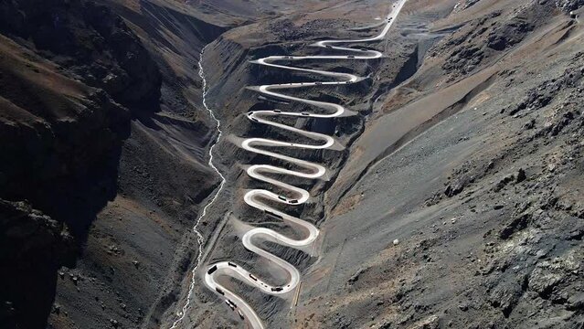 Aerial dolly tilt-down view of the cuesta caracoles road, border between Chile and Argentina (Mendoza). Cargo trucks going down the route