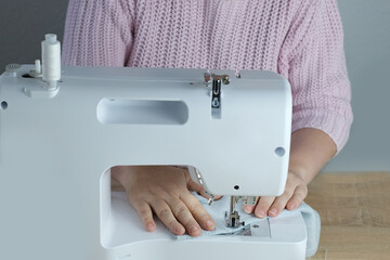 close-up of female hands perform work on white sewing electric computer machine, stitches appear step by step on fabric, concept of tailoring, women's hobby, seamstress profession, modern needlework