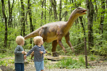 two kid boys walking in forest at dinosaurs park