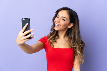 Young caucasian woman isolated on purple background making a selfie with mobile phone