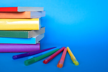 books stacked with the colors of the lgtb flag and pens of the same color on a blue background with...