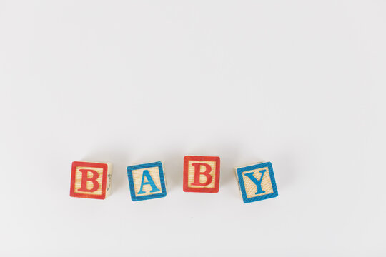 An arrangement of children painted alphabet wooden blocks spelling out "baby" isolated in a white background with text copy space. 