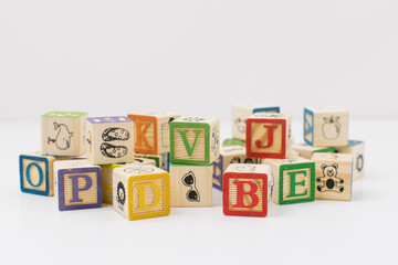 A pile of children painted alphabet wooden blocks isolated with white background for text copy...