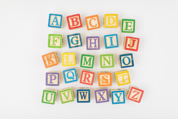 An arrangement of children painted alphabet wooden blocks isolated with white background for text copy space.  - Powered by Adobe