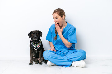Young veterinarian woman with dog sitting on the floor isolated on white background with surprise and shocked facial expression