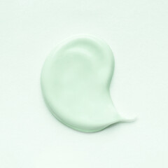 Light green smear of cosmetic clay or cream on a pastel background.