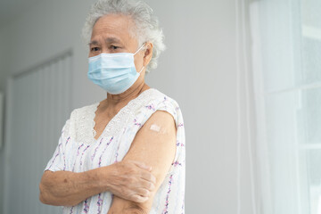 Elderly Asian senior woman wearing face mask getting covid-19 or coronavirus vaccine by doctor make injection.