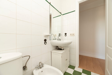 Fototapeta na wymiar Bathroom with wooden furniture in white with porcelain sink, frameless mirror on the wall and white and green tiled floors