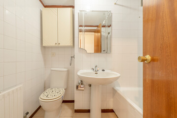Bathroom with mirror, porcelain sink with foot of the same material, white tub and aluminum radiator