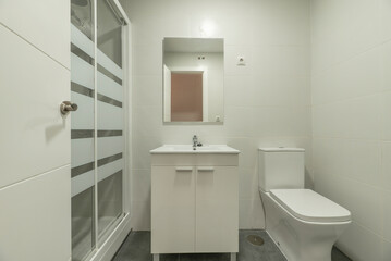 Newly renovated bathroom with a square frameless mirror, a porcelain sink with a high gloss white wood cabinet, a walk in shower and white tile
