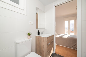 Bathroom with wooden cabinet with white porcelain sink, square frameless mirror and access to a bedroom with terrace