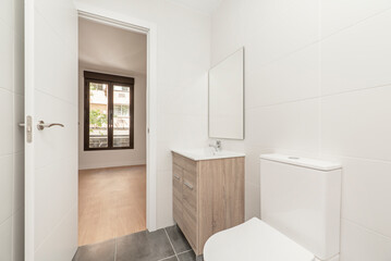 Bathroom with wooden cabinet with drawers, white porcelain sink, square frameless mirror, glass shower stall and white tiles