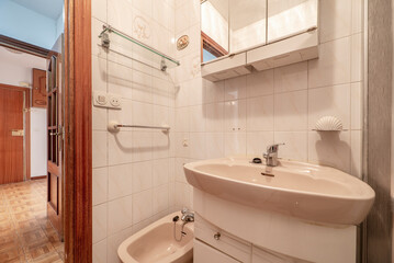 wc with white wooden bathroom cabinet with mirror, pink porcelain sanitary ware and glass shelves