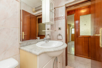 wc with white wooden bathroom cabinet with matching mirror, white marble countertop and exit to a corridor with a wooden map