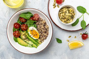 Keto diet plate quinoa, avocado, egg, tomatoes, spinach and sunflower seeds on light background. Healthy food, ketogenic diet, diet lunch concept, place for text, top view