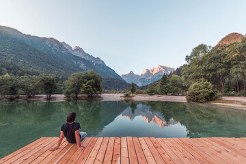 Man on the pier at the Jasna Lake in Kranjska Gora observing the amazing mountain landscape