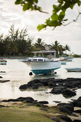 Fototapeta premium Yachts and fishing boats on the shore with black large stones with mountain range in the background