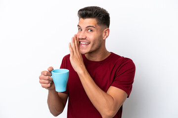 Young caucasian man holding cup of coffee isolated on white background whispering something