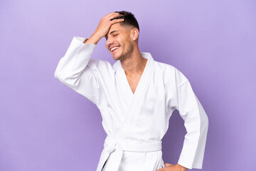 Young caucasian man doing karate isolated on purple background smiling a lot