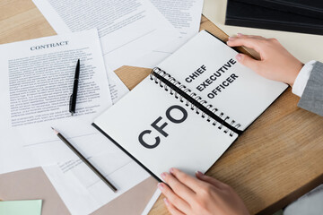 cropped view of woman holding notebook with cfo and chief executive officer lettering.