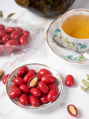tea party with healthy sweets. A mug of tea and a plate of almond nuts in chocolate glaze. Almost top view.