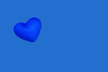 Un corazón azul de fieltro hecho a mano sobre un fondo azul liso y aislado. Vista superior y de cerca. Copy space