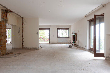 Large bright room with many windows of an old villa undergoing demolition and renovation. The walls...