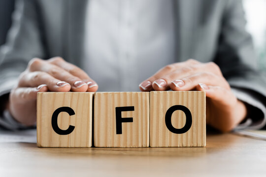 cropped view of woman holding wooden cubes with cfo lettering in office.
