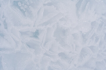 Obraz premium Macro photo of transparent light blue ice of frozen Baikal lake with white frost ornament. Beautiful winter nature background.