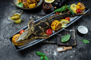 Baked fish sturgeon with vegetables and potatoes on dark background. banner, menu, recipe place for text