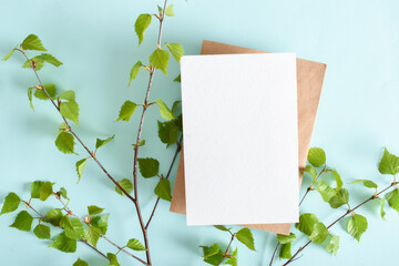 A mock-up of an envelope, a white sheet of paper and birch branches on a light blue background.