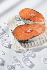 frozen salmon red fish steaks on a white plate with ice on a white background