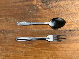 stainless steel spoon and fork on wooden table