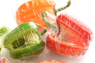 Bell pepper with cling film or plastic food wrap on white background.