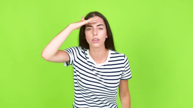 Young brunette woman looking far away with hand to look something over isolated background. Green screen chroma key