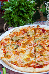 classic Italian pizza with ham, tomatoes and pickles on a dark background in rustic style