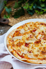 classic Italian pizza with chicken and pineapples on a dark background in rustic style